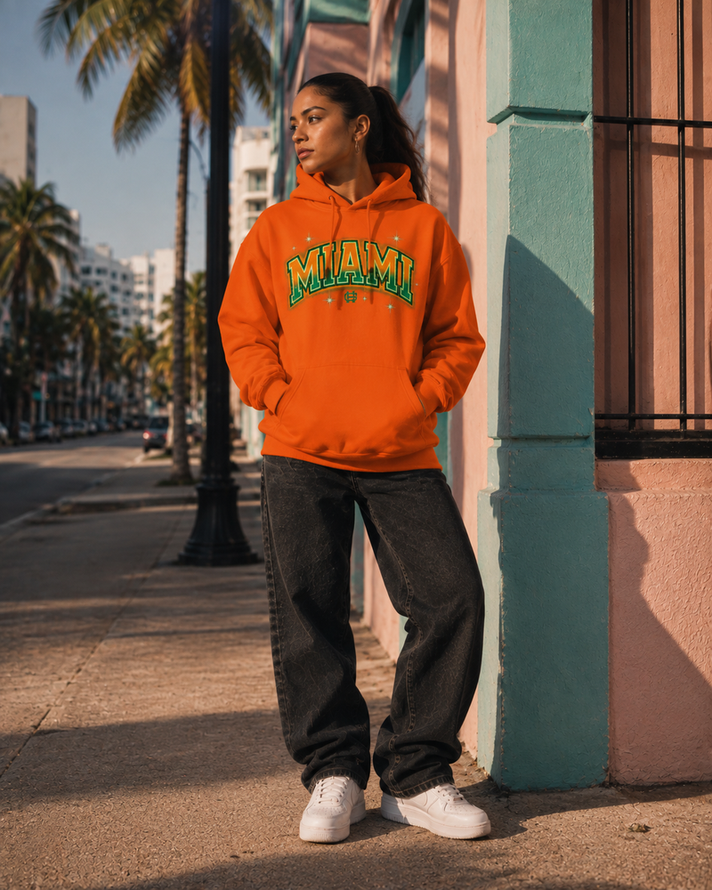 Model wearing the orange Miami Airbrush Fleece Hoodie in a sunlit Miami street scene