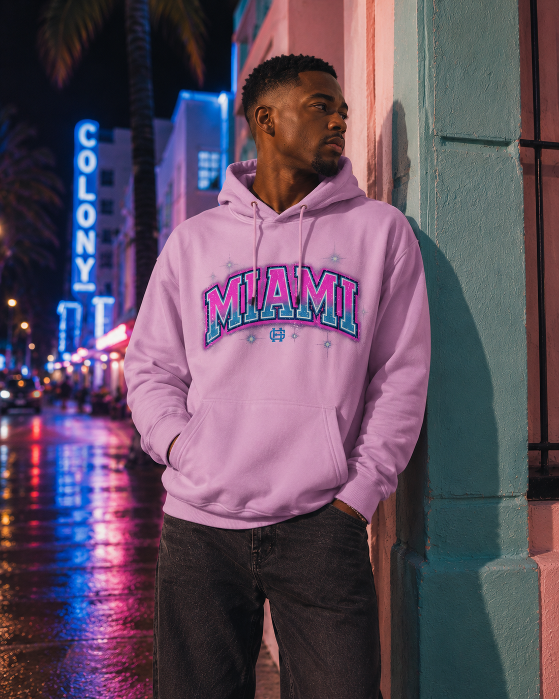 Model wearing the Miami Airbrush Fleece Hoodie in Vice pink with pink and teal Miami artwork, front lifestyle view